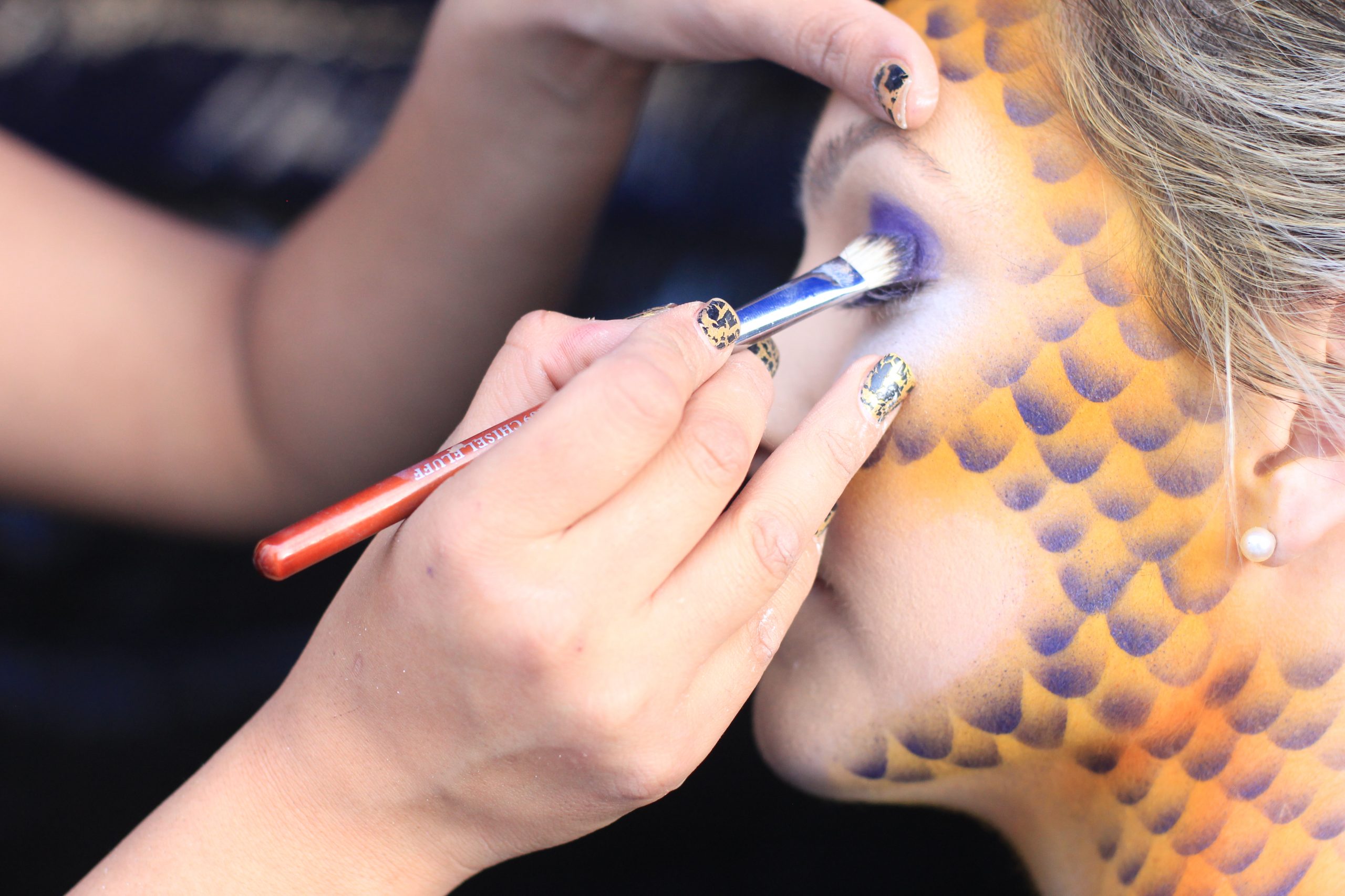Behind the scenes proof of concept image showing mermaid inspired scale makeup being applied to a model for the Wild Mermaids project