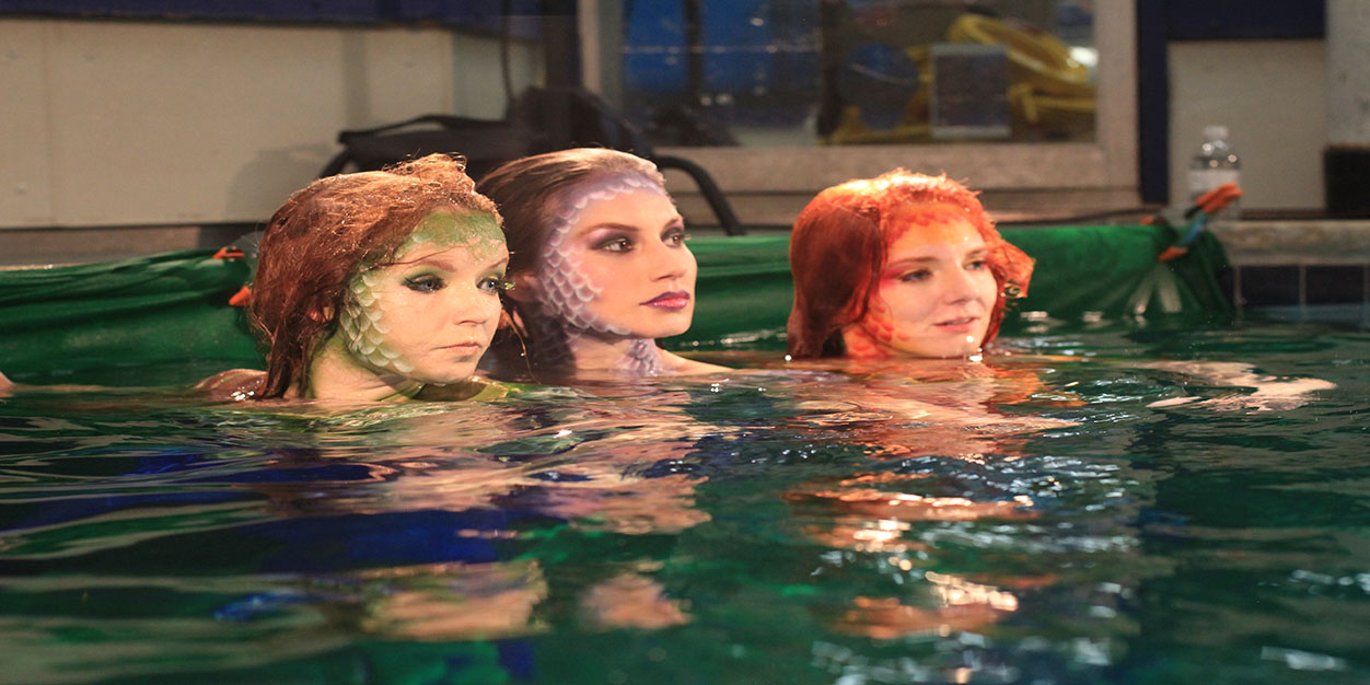 Behind the scenes proof of concept image showing three women in mermaid makeup partially submerged in water during the Wild Mermaids test shoot